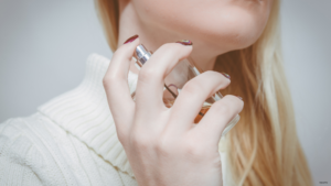 woman spraying perfume on her neck